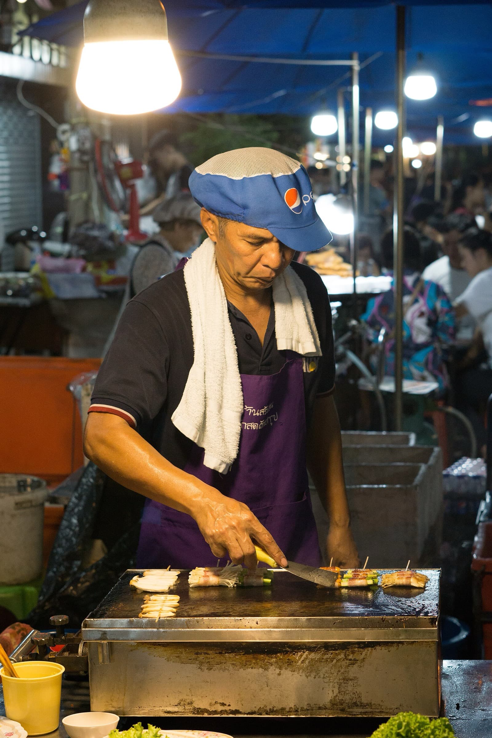 Vendeur de rue préparant à manger sur un marché de Bangkok